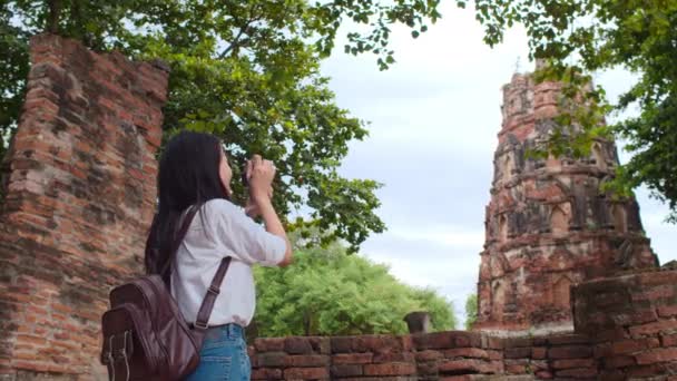 タイのアユタヤで休暇を過ごしながら写真を撮るためにカメラを使用している旅行者アジアの女性 日本の女性観光客は 伝統的な街の素晴らしいランドマークで彼女の旅をお楽しみください スローモーション — ストック動画