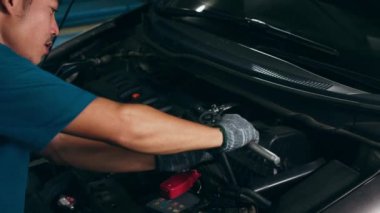 Araba tamircisinin tamir istasyonunda kaldırılan otomobilin motoruyla ilgili detaylar. Geceleri tamirci garajında araba tamir eden Asyalı yetenekli bir adam. 4k ağır çekim.
