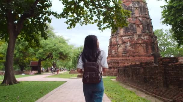 タイのアユタヤで休暇を過ごす旅行者アジアの女性 日本のバックパッカーの女性は 伝統的な都市の素晴らしいランドマークで彼女の旅をお楽しみください ライフスタイルの女性旅行休日のコンセプト — ストック動画