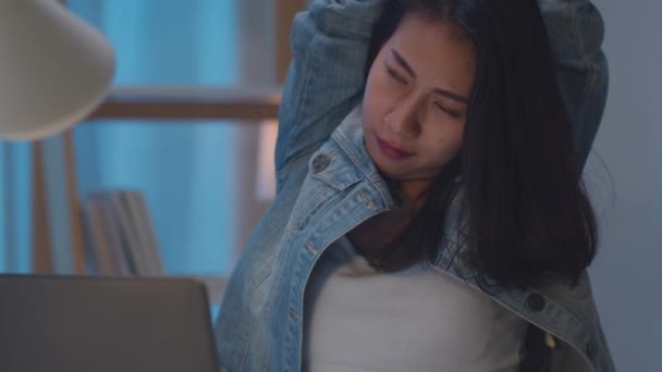 スローモーション 千年紀の若い中国のビジネスマンの女性は 椅子の上で夜遅くまでストレッチ 現代の家庭でのリビングルームでラップトップコンピュータを探しています アジアの人々職業燃焼症候群の概念 — ストック動画