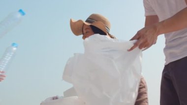 Asyalı mutlu aile eylemcileri plajda plastik atık topluyor. Asyalı gönüllüler doğayı temizlemeye ve çöpleri toplamaya yardım eder. Çevre kirliliği sorunları hakkında bir kavram. 4k Ağır çekim.