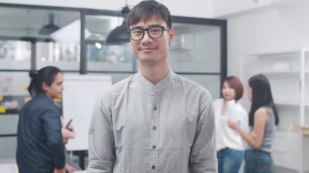 カメラと笑顔を見て成功したハンサムな経営者のビジネスマンのスマートカジュアルウェアの肖像画は 腕が現代のオフィスの職場で交差した 現代の会議室に立つ若いアジアの男 — ストック動画