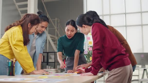 Asiatische Geschäftsleute und Geschäftsfrauen treffen Brainstorming-Ideen über kreative Web-Design-Planungsanwendung und entwickeln Vorlagen-Layout für Mobiltelefon-Projekt, das in kleinem Büro zusammenarbeitet.