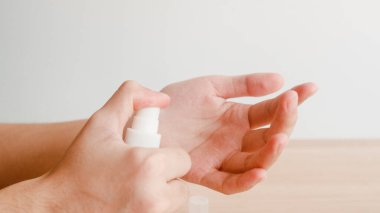 Koronavirüsü korumak için el dezenfektanı kullanan Asyalı bir kadın. Kadın, sosyal uzaklık evde kalıp kendini karantinaya alırken alkol şişesini hijyen için temizlemeye zorlar..