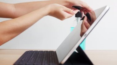 Koronavirüsü korumak için tablet kullanmadan önce Asyalı kadın alkol jeli dezenfektanı kullanıyor. Kadın, sosyal uzaklık evde kaldığında ve kendini karantinaya aldığında, alkolü temizlik için zorlar..