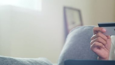 Sosyal uzaklık evde kalırken ve karantina süresi, çevrimiçi alışveriş, koronavirüs konsepti kullanırken, ev bilgisayarını, kredi kartını kullanan Asyalı kadın oturma odasından e-ticaret interneti satın alıp satın alıyor..