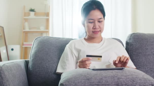 使用平板电脑 信用卡在客厅里购买电子商务互联网的亚洲女性在社交场合待在家里和自我隔离时间 网上购物 — 图库视频影像