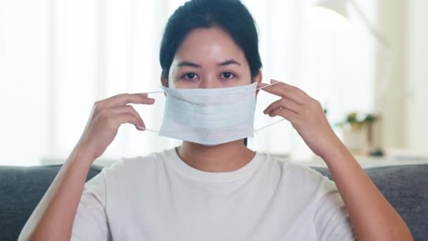 Karartıcı Asyalı Kadını Koruyucu Maske Takıyor Oturma Odasındaki Koltukta Oturuyor — Stok video