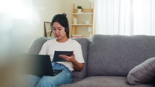 アジアのフリーランスビジネス女性家庭での社会的距離滞在と自己隔離時間の自宅からリビングルームで職場で顧客とノートパソコンのワーキングコールビデオ会議を使用してカジュアルウェア — ストック動画