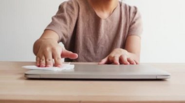 Koronavirüsü korumak için açılmadan önce dokulara alkol spreyi sıkan Asyalı bir kadın. Sosyal uzaklık evde kaldığında ve kendini karantinaya aldığında hijyen için kadın bilgisayarı.