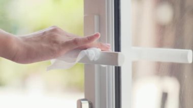 Koronavirüsü korumak için kapıyı açmadan önce mendil kapağına alkol spreyi sıkan Asyalı bir kadın. Sosyal uzaklık evde kaldığında ve kendini karantinaya aldığında hijyen için kadın temiz yüzey.