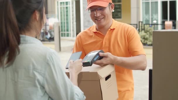 年轻的邮递员拿着邮件箱给顾客 亚洲妇女在手机上签了名 并通过Qr码付款 以便在室外接收包裹 4K慢动作 — 图库视频影像