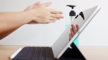 Koronavirüsü korumak için tablet kullanmadan önce Asyalı kadın alkol jeli dezenfektanı kullanıyor. Kadın, sosyal uzaklık evde kaldığında ve kendini karantinaya aldığında, alkolü temizlik için zorlar..