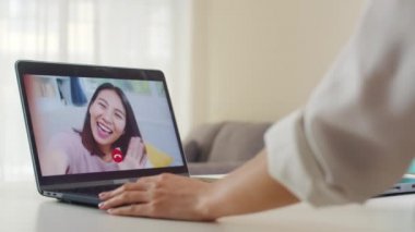 Genç Asyalı iş kadını evde çalışırken bilgisayarla arkadaşlarıyla konuşuyor. Kişisel izolasyon, sosyal uzaklık, bir sonraki normal konseptte koronavirüs için karantina.