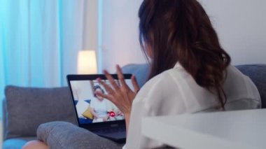 Asya 'lı öğrenci değişim programında dizüstü bilgisayar kullanarak ailenle konuşarak gece oturma odasında çalışırken. Kişisel izolasyon, sosyal uzaklık, koronavirüs için karantina.