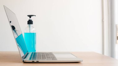 El hijyen için el dezenfektanı jeli bilgisayar laptopuyla birlikte Corona virüsü koruması. Sosyal mesafeler evde ve kendi kendine karantina süresi, online alışveriş, koronavirüs konsepti.