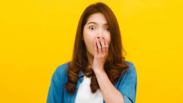 Portrait of young Asian lady with positive expression, joyful surprise funky, dressed in casual clothing and looking at the camera over yellow background. Happy adorable glad woman rejoices success.