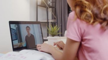 Genç Asya 'lı kız öğrencilerin arka planda kulaklık takması, internet öğretmeniyle uzaktan öğrenme dersi alması ve evde bilgisayar ekranında ders çalışması. Corona virüsünün önlenmesi için sosyal mesafe ve karantina.
