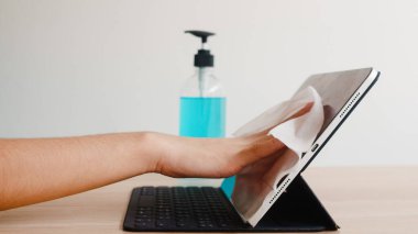 Koronavirüsü korumak için açılmadan önce temiz doku tabletine alkol spreyi sıkan Asyalı bir kadın. Sosyal uzaklık evde kaldığında ve kendini karantinaya aldığında hijyen için kadın temiz yüzey.