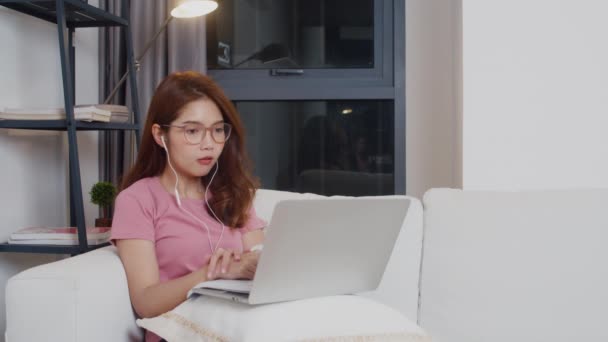 若いアジアの10代の女の子の学生は 自宅から自宅で自宅のリビングルームでラップトップ上のオンライン教師とヘッドフォンの距離学習レッスンを着用しています 社会的距離 コロナウイルス予防の隔離 — ストック動画