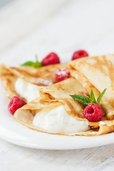 Homemade sweet crepes with cottage cheese, mint and raspberry, closeup