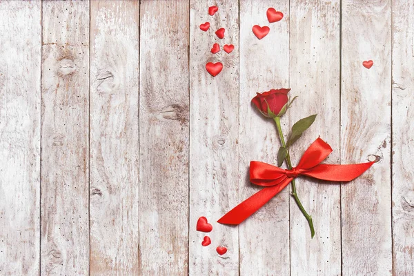 Piękna czerwona róża ze wstążki i serca na tle drewnianych — Zdjęcie stockowe