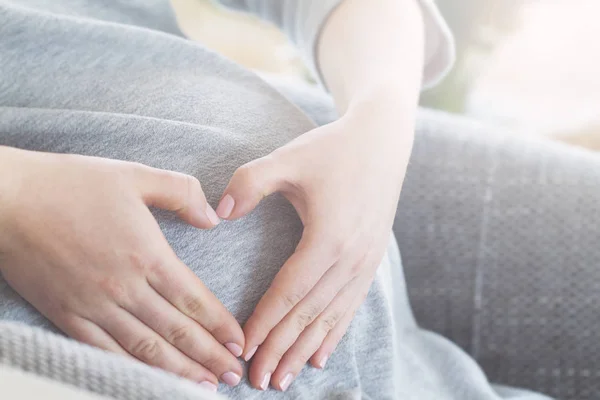 Schwangere hält ihre Hände auf ihrem geschwollenen Bauch — Stockfoto