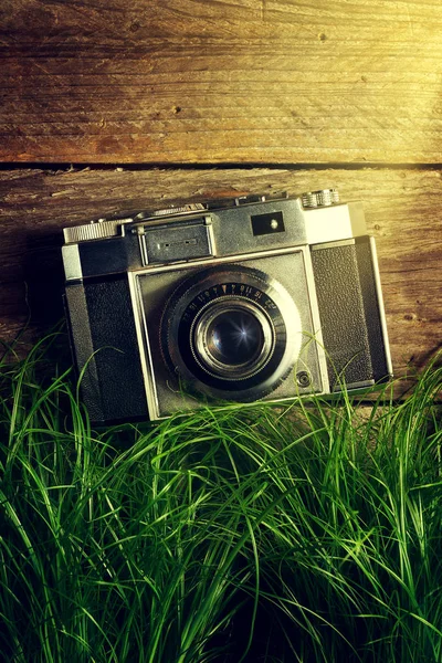 Старая винтажная камера в зеленой траве со световыми балками на деревянном баке — стоковое фото