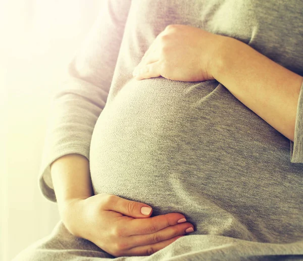 Unga gravid kvinna håller händerna på magen svullen. Kärlek-konceptet — Stockfoto