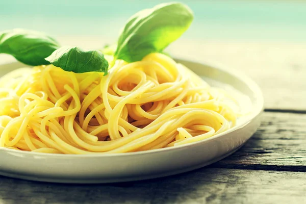 Gustosi spaghetti colorati cucinati con basilico fresco sul piatto — Foto Stock