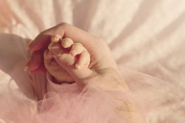 Küçük şirin bebek eller anne elinde. Pembe bir arka plan. 