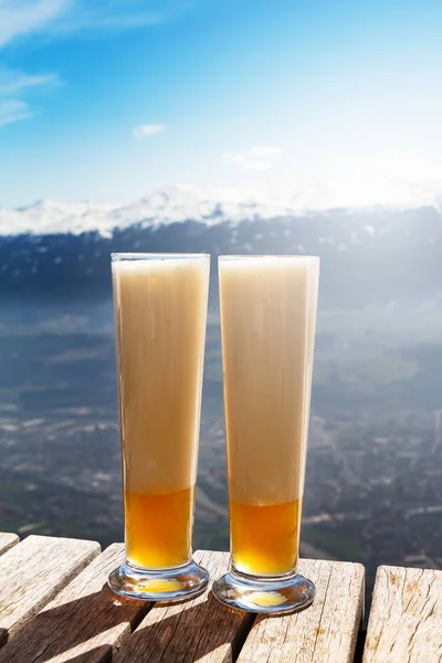 Sabrosa cerveza fría hermosa en una mesa de madera en el fondo de la montaña —  Fotos de Stock