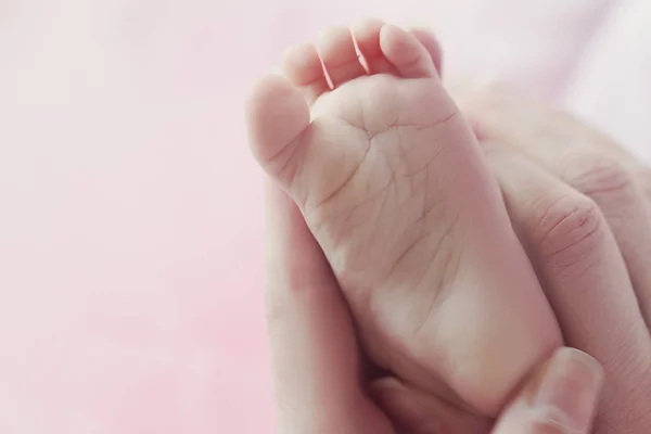 Closeup matky ruce držící roztomilé malé dítě nohy, ukazuje dítě — Stock fotografie