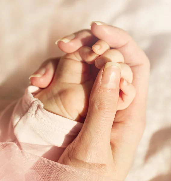 Malé roztomilé dítě ruce v matce ruku. Růžový pozadí. — Stock fotografie