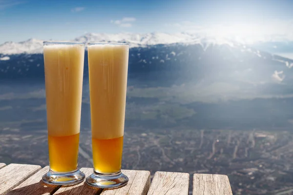 Belle bière fraîche sur une table en bois sur fond de montagne — Photo