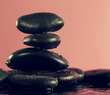 Güzel pembe Spa sıcak taşlar su ıslak zemin üzerine. Yan kompozisyon. 