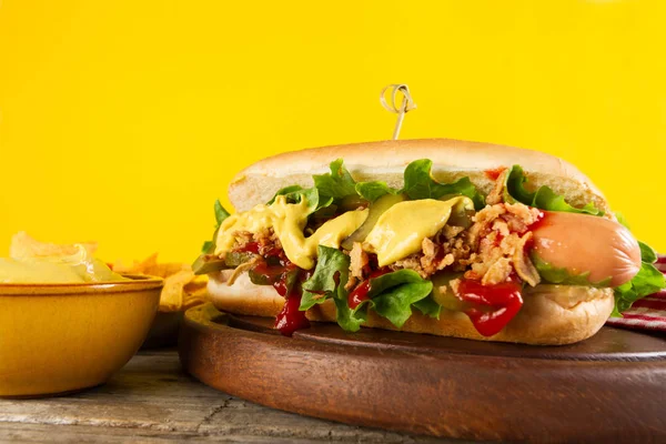 Gustoso classico hot dog tradizionale su tavola di legno su sfondo giallo . — Foto Stock
