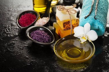 Güzel Spa Set Spa ürünleri ile temel yağlar, sabun, havlu, Spa deniz tuzu karanlık ıslak zemin üzerine. Yatay kopya alanı ile. 