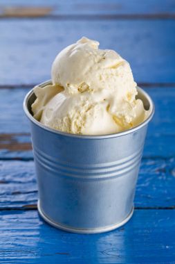 Lezzetli vanilyalı dondurma kaşık toz kase üzerinde mavi ahşap rustik masa. 