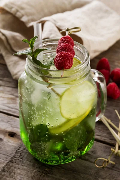 Sabrosa bebida fresca fría limonada con limón, menta, frambuesa, hielo —  Fotos de Stock
