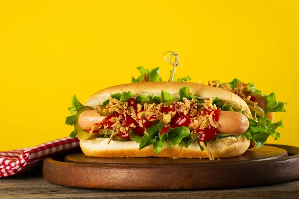 Gustoso classico hot dog tradizionale su tavola di legno su sfondo giallo — Foto Stock
