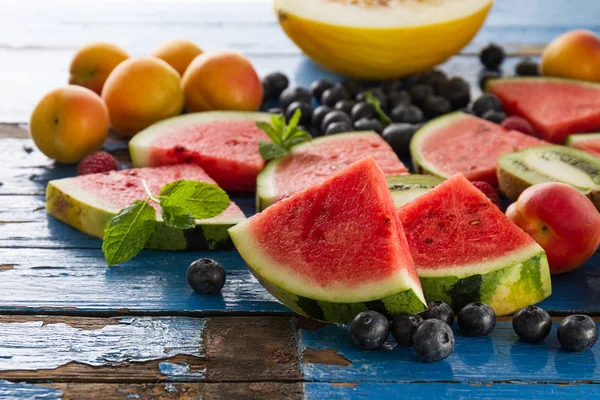 Variedad de sabrosas frutas frescas y apetitosas en madera azul — Foto de Stock