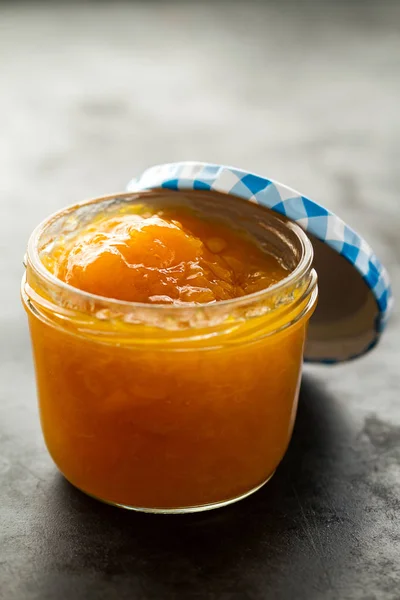 Tasty fruit orange apricot jam in glass jar on dark table — Stock Photo, Image