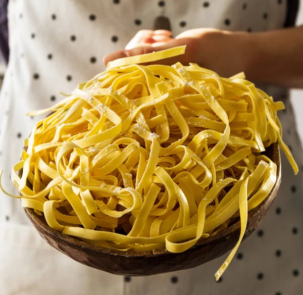 Feminine hands cook holding tasty fresh raw traditional italian pasta — Stock Photo, Image