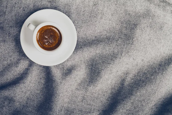 Tasty coffee espresso in small cup on grey plaid. Home concept. — Stock Photo, Image