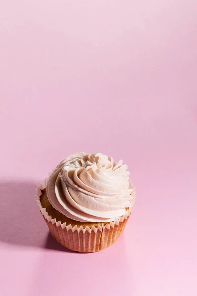 Nahaufnahme von leckeren Cupcakes mit Sahne. rosa Hintergrund. — Stockfoto
