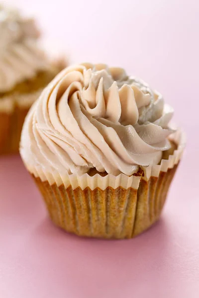 Nahaufnahme von leckeren Cupcakes mit Sahne. rosa Hintergrund. — Stockfoto