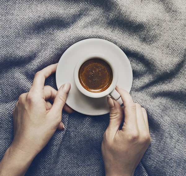 Woman hands holding tasty coffee espresso in small cup on grey plaid — Stock Photo, Image