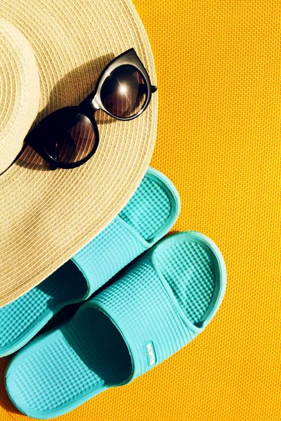 Vackra stråhatt med solglasögon och blå flip flops på gula — Stockfoto