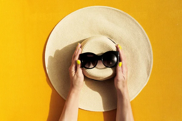Händerna på ung flicka håller stråhatt och solglasögon på levande — Stockfoto